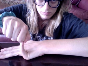 Image: Me, Beth, stretching my pinky finger on my left hand back to a ninety-degree angle. 
